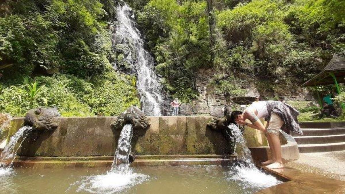 Seorang pengunjung membasuk muka di destinasi wisata Air Terjun Sumuran, Ngablak, Kabupaten Magelang, Jawa Tengah