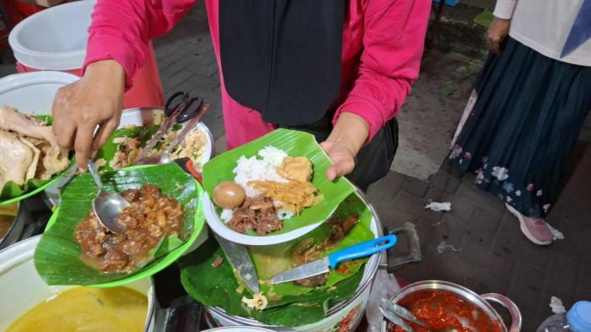 GUDEG - Karyawan Gudeg Koyor Mbok Sireng tampak sedang melayani pembeli di Waroeng Semawis, Sabtu (4/10/2025) malam. Antusiasme pengunjung terhadap pembukaan kembali Waroeng Semawis tak hanya dirasakan dari keramaian pengunjung, tetapi juga dari penjual yang merasakan langsung lonjakan pembeli di hari pertama.