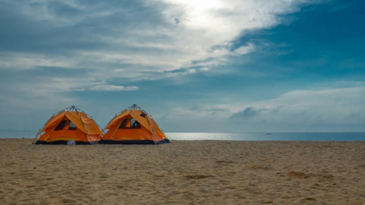 Ilustrasi camping di pantai sambil menikmati keindahan alam.