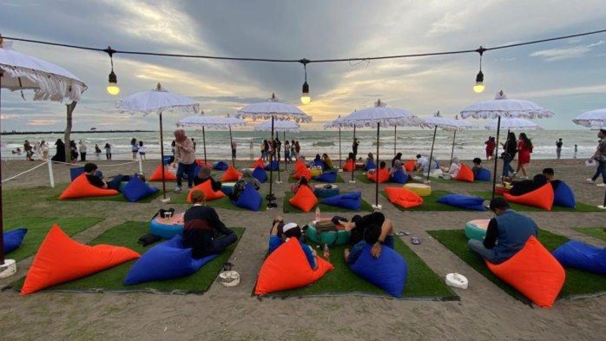 CERITA PANTAI - Pengunjung sedang menikmati senja di Cerita Pantai area Pantai Indah Bosowa Makassar, Sabtu (15/2/2025). Cerita Pantai hadir dengan konsep terbaru dan banyak varian menu.