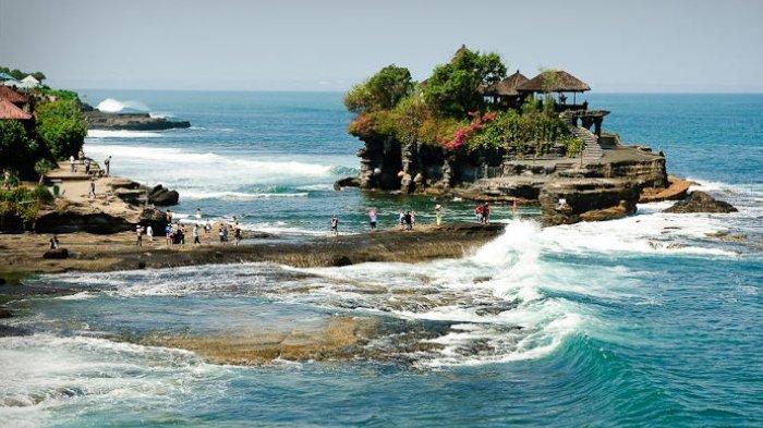 Pemandangan Tanah Lot, Bali dengan pura di atas batu karang besar.