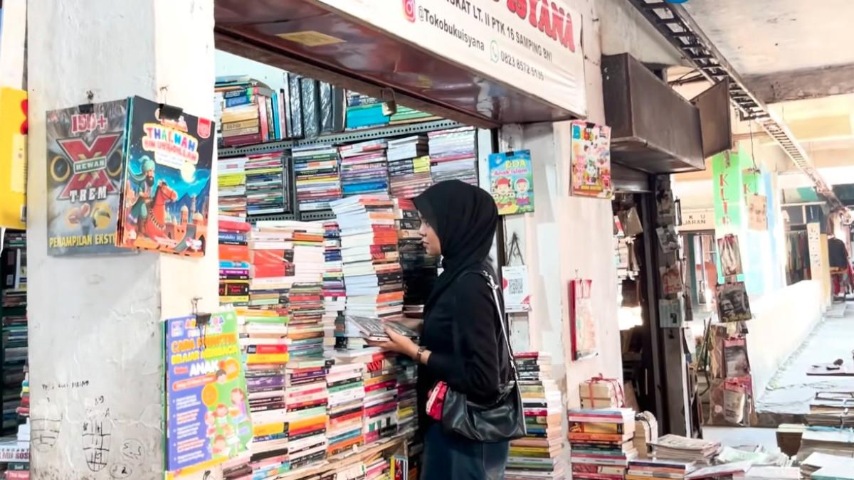 Pengunjung memeriksa kondisi buku sebelum membeli di kios lantai dua Padang Teater.