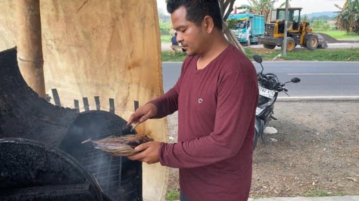 ASAPI IKAN - Putra mengasap ikan laut menggunakan bonggol jagung di warung Sego Sambel Asapan, Ambarawa, Kabupaten Semarang, Jumat (29/8/2025) sore. Tempat makan sederhana itu mendadak viral di media sosial karena cita rasa khas dan suasana pedesaan yang autentik.