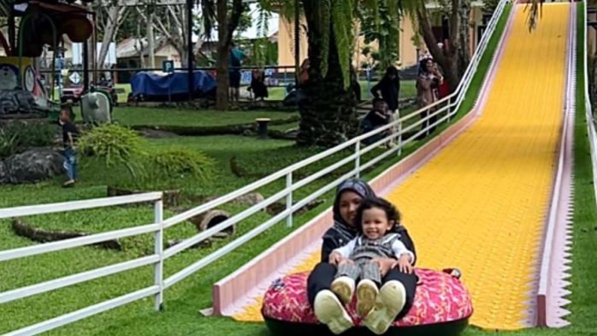 WAHANA PERMAINAN — Seorang anak dan ibu, saat memainkan wahana yellow slide di obyek wisata Sanggaluri Park, Minggu (31/8/2025).