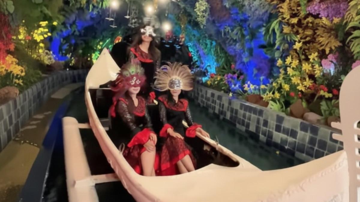 Wisatawan nyobain wahana perahu Magic Journey dengan memakai topeng.