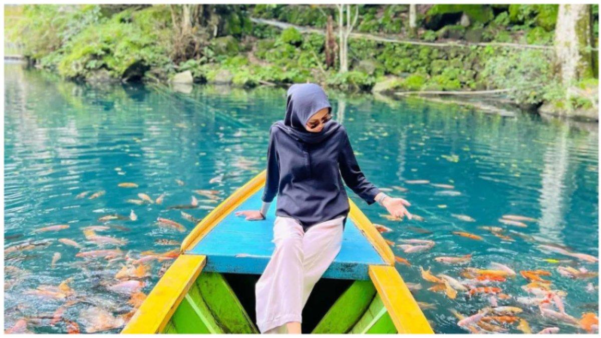 Wisatawan menaiki perahu yang dibawahnya banyak sekali ikan berwarna-warni di Telaga Biru Cicerem. Simak harga tiket masuk tempat wisata di Kuningan untuk libur Lebaran