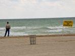 seorang-pria-dan-papan-peringatan-rip-current.jpg