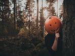 seorang-pria-yang-mengenakan-kostum-halloween-sedang-bersembunyi-di-balik-pohon.jpg