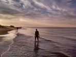 wisatawan-yang-menikmati-sunset-sambil-bermain-air-di-pantai.jpg