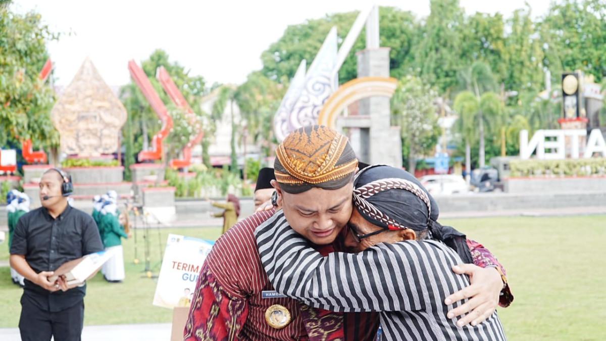 HARI GURU NASIONAL - Bupati Klaten Hamenang Wajar Ismoyo memeluk  Sugimo Guru Pendidikan Olahraga dan Kesehatan Jasmani SMA Negeri 2 Klaten, tempat Hamenang menempuh pendidikan pada 2003–2006 yang pernah mendidiknya, Selasa (25/11/2025) setelah upacara Hari Guru Nasional di Alun-alun Klaten.
