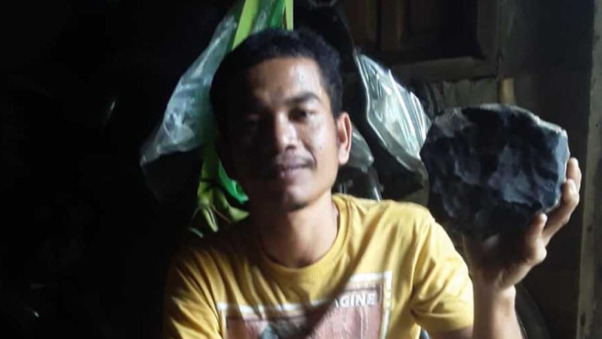 HARGA BATU METEOR - Josua Hutagalung (33) warga Dusun Sitahan Barat, Desa Satahi Nauli, Kecamatan Kolang, Kabupaten Tapanuli Tengah menunjukkan batu yang diduganya sebagai meteor setelah jatuh menimpa rumahnya, Sabtu (1/8/2020).