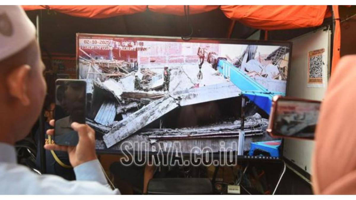 PONPES AMBRUK - Keluarga memantau evakuasi korban bangunan runtuh di ponpes Al Khoziny, Buduran, Sidoarjo dari layar yang disediakan di posko Basarnas, Kamis (2/10/2025). Evakuasi korban bangunan runtuh mulai menggunakan alat berat. Sosok dr Aaron Franklyn Suaduon Simatupang, melakukan proses amputasi terhadap korban ambruknya bangunan Pondok Pesantren (Ponpes) Al Khoziny, Sidoarjo.