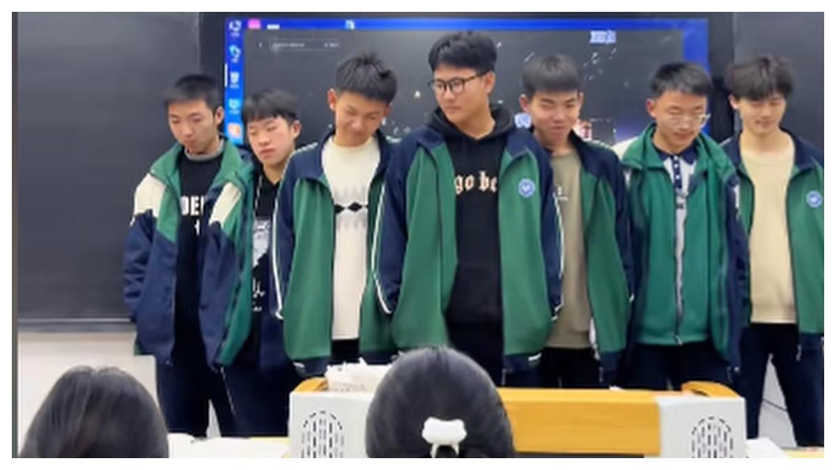 Para siswa yang terlambat bersiap untuk tampil di podium sementara teman-teman sekelas mereka menyaksikan.