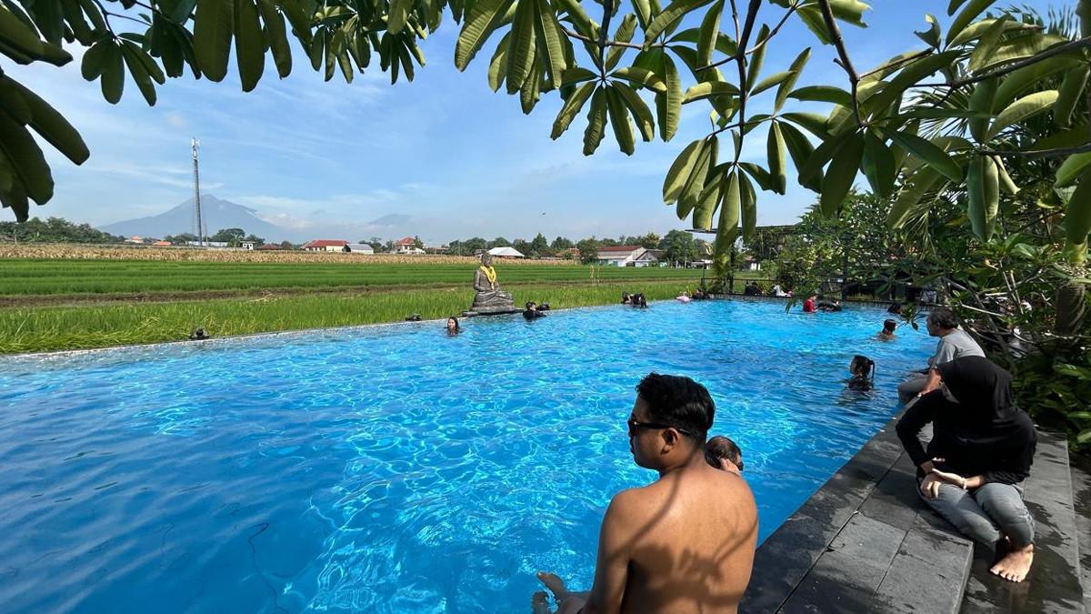 WISATA DI KLATEN - Pengunjung duduk di tepi kolam Candramaya Pool and Resort Klaten dengan panorama sawah dan gunung, Minggu (28/12/2025).