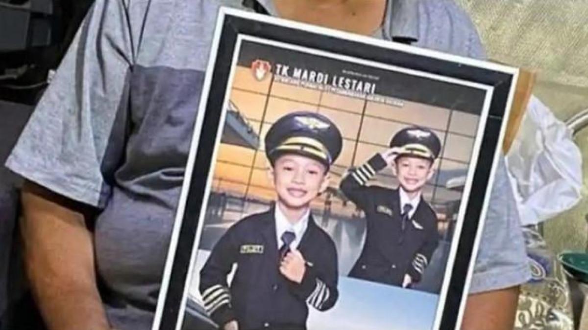 KEMATIAN ALVARO - Tugimin (71) memegang foto cucunya, Alvaro Kiano Nugroho (6), mengenakan seragam pilot saat kegiatan sekolah di TK Mardi Lestari. Polisi mengungkap manipulasi ayah tirinya, Alex Iskandar, yang berpura-pura mencari Alvaro, padahal justru menjadi pelaku penculikan dan pembunuhan.