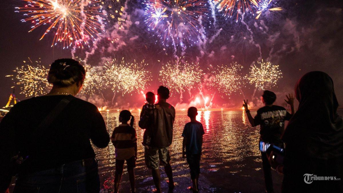 Warga menyaksikan kembang api saat merayakan Tahun Baru di Pantai Ancol, Jakarta pada 1 Januari 2025.