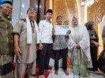 Baharuddin-43-bersama-pengurus-Masjid-Babussaadah-saat-mendapatkan-sertifikat-umrah-gratis.jpg