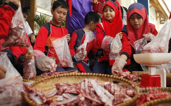 ILUSTRASI - Sejumlah siswa membantu membungkus dan menimbang daging kurban yang sudah dipotong-potong 