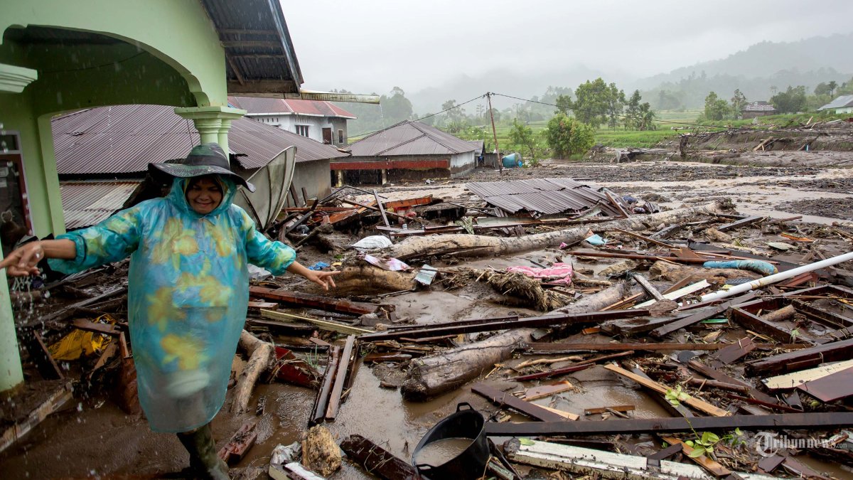 BANJIR DAN LONGSOR - Seorang wanita berdiri di dekat rumah yang rusak setelah banjir bandang di Kabupaten Agam, Sumatera Barat, Indonesia, 27 November 2025