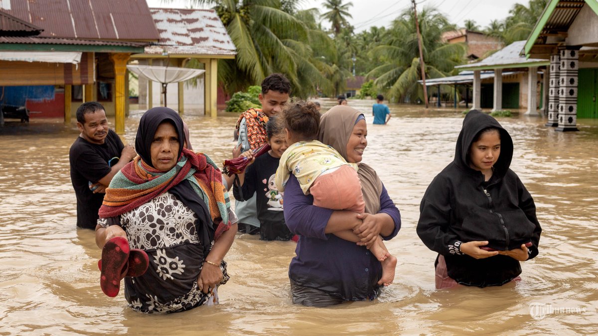 BANJIR DAN LONGSOR - Warga berjalan melewati banjir setelah hujan deras melanda Kabupaten Padang Pariaman, Sumatera Barat, Indonesia, 24 November 2025. (Photo by Andri Mardiansyah/Xinhua)