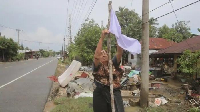 BENDERA PUTIH - Bendera putih berkibar di jalan lintas Aceh–Medan, simbol keputusasaan warga terdampak banjir bandang.