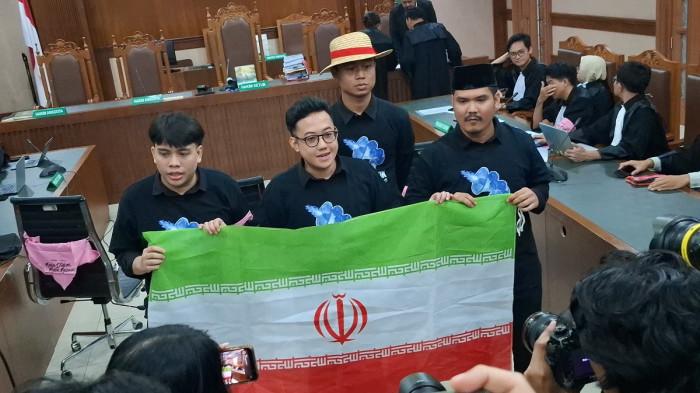 SIDANG DEMO AGUSTUS - Delpedro dkk membentangkan bendera negara Iran, jelang sidang vonis kasus dugaan penghasutan aksi demo Agustus 2025 lalu yang menjerat mereka, di Pengadilan Negeri Jakarta Pusat, Jumat (6/3/2026).