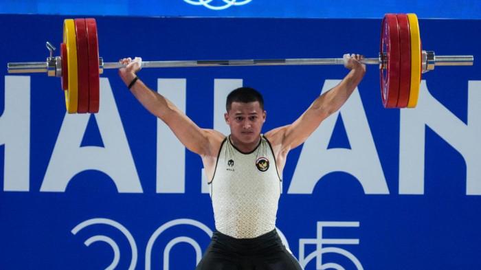 EMAS DAN CETAK REKOR - Lifter andalan Indonesia, Rizki Juniansyah, sukses mempersembahkan medali emas pada ajang SEA Games Thailand 2025 sekaligus mencatatkan sejarah dengan memecahkan rekor dunia pada angkatan clean and jerk (C&J) seberat 205 kilogram dan angkatan total seberat 365 kg.