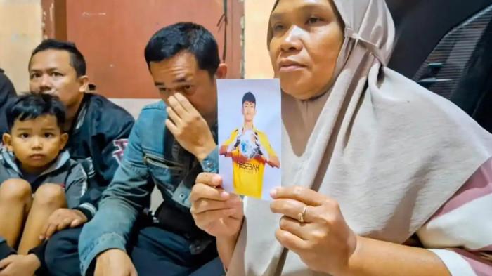 TUNJUKKAN FOTO - Imas Siti Rohanah (52) warga Kelurahan Pesawahan, Kecamatan Dayeuhkolot, Kabupaten Bandung sedang memegang foto cucunya Riski Nur Fadhilah (18). Fadhil diduga ditipu oleh seseorang yang mengaku menjadi manajer klub profesional asal Medan dan kini sedang kerja paksa di Kamboja.