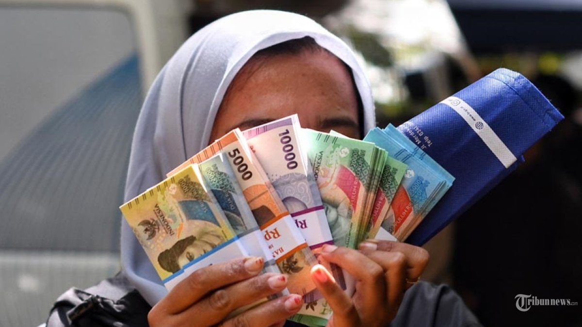 UANG BARU - Warga menukarkan uang di mobil kas keliling Bank Indonesia Malang di Taman Merjosari, Kota Malang, Jawa Timur, Kamis (19/2/2026). Bank Indonesia Malang mulai membuka layanan penukaran uang rupiah baru dalam rangka memenuhi kebutuhan masyarakat jelang lebaran 2026. Layanan penukaran uang rupiah di wilayah kerja Bank Indonesia Malang ini dibuka mulai 19-26 Februari 2026 untuk kas keliling dan 26-27 Februari 2026 untuk loket perbankan. SURYA/PURWANTO