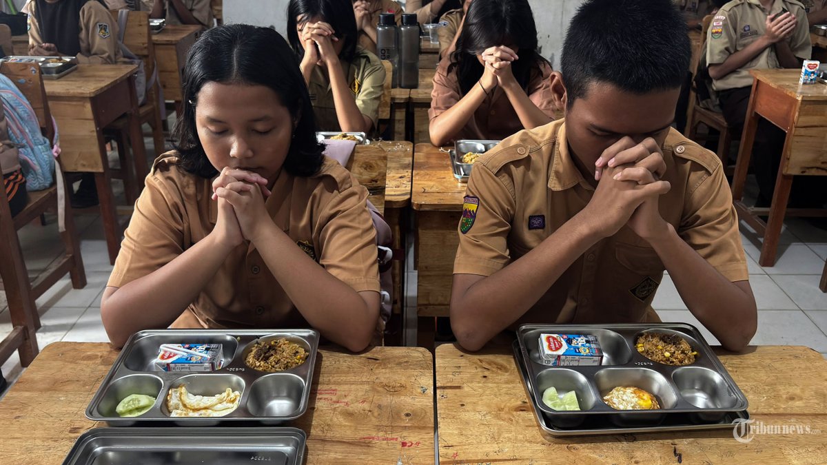 MENU MBG - Siswa berdoa sebelum menyantap makanan program Makan Bergizi Gratis (MBG) yang diterimanya di SMA Negeri 21, Medan, Sumatra Utara, Jumat (17/10/2025). Menu spesial MBG kali ini nasi goreng telur ceplok yang disajikan serentak di seluruh Indonesia, bertepatan memperingati hari ulang tahun Presiden Prabowo. TRIBUN MEDAN/DANIL SIREGAR
