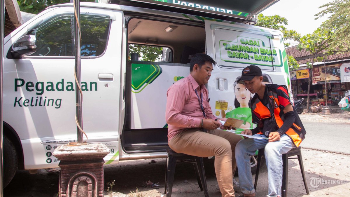 SOSIALISASI - Petugas Pemasaran Pegadaian, Satriyo Hanggoro (kiri) sedang berinteraksi dengan calon nasabah, Rudi Saputra di Unit Pegadaian Keliling yang sedang berada di Pasar Sukodono, Sragen, Jumat (26/9/2025). Pegadaian hadir di tengah denyut nadi pasar untuk menjangkau nasabah lebih luas, dan melakukan sosialisasi kepada masyarakat tentang program Tabungan Emas, terutama untuk kawula muda sekaligus menyeleraskan program pemerintah untuk MengEmaskan Indonesia. Tribun Solo/Muhammad Nursina