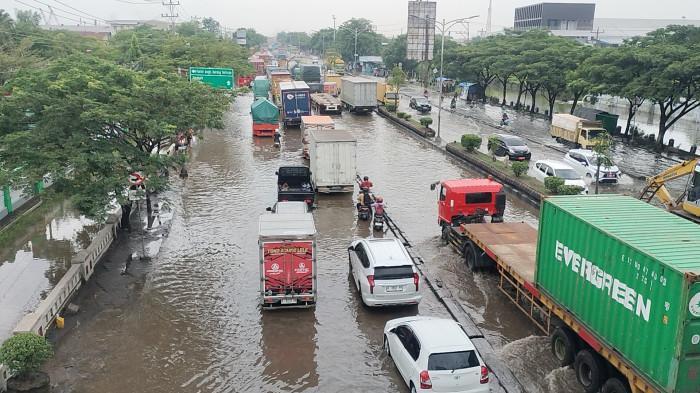 Pengendara mendorong motor yang mogok akibat banjir di Jalan Kaligawe, Semarang Timur. Genangan air melumpuhkan arus lalu lintas sejak Selasa sore.