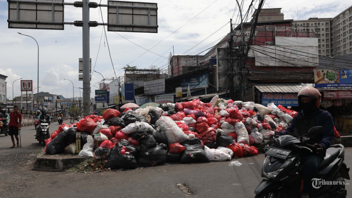 MENUMPUK - Pengendara melintas di dekat tumpukan sampah di Jalan Dewi Sartika, Ciputat, Tangerang Selatan, Banten, Sabtu (13/12/2025). Penumpukan sampah tersebut terjadi dikarenakan tempat pembuangan akhir (TPA) Cipeucang, Serpong, tengah dalam perbaikan sehingga mengganggu proses pengangkutan sampah di beberapa wilayah Tangerang Selatan. TRIBUNNEWS/IRWAN RISMAWAN