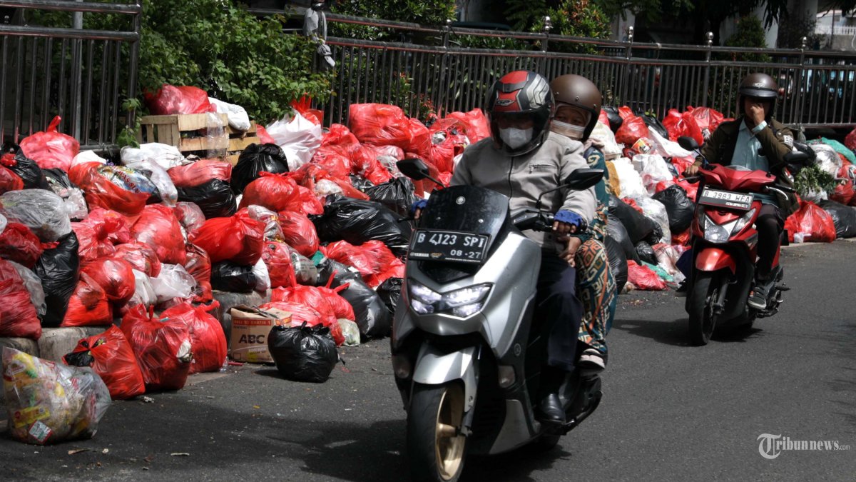 MENUMPUK - Pengendara melintas di dekat tumpukan sampah di Jalan Dewi Sartika, Ciputat, Tangerang Selatan, Banten, Sabtu (13/12/2025). Penumpukan sampah tersebut terjadi dikarenakan tempat pembuangan akhir (TPA) Cipeucang, Serpong, tengah dalam perbaikan sehingga mengganggu proses pengangkutan sampah di beberapa wilayah Tangerang Selatan. TRIBUNNEWS/IRWAN RISMAWAN