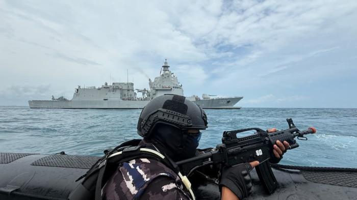 LATIHAN TNI AL - Prajurit TNI AL bersenjata laras panjang melakukan operasi Visit Board Search and Seizure (VBSS) dari perahu karet di perairan Bangka Belitung. Di latar belakang tampak kapal perang KRI yang ikut dikerahkan dalam latihan anti akses dan amfibi.