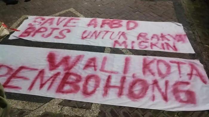 KANTOR BPJS DENPASAR - Polisi selidiki teor yang terjadi di Kantor BPJS Kesehatan Cabang Denpasar di Jalan D.I. Panjaitan, Renon, Bali, Sabtu 21 Februari 2026 malam. Spanduk yang dibentangkan di Kantor BPJS Kesehatan Denpasar, pada Sabtu 21 Februari 2026 malam. Polisi Selidiki Penyerangan Kantor BPJS Denpasar Bali: Pelaku Berkelompok Gunakan Masker