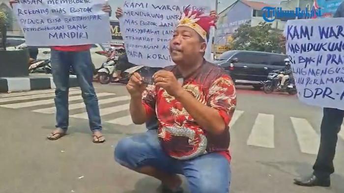 Dalam Foto: Perwakilan Aktivis Anti-Korupsi Kota Depok, Kasno, melakukan aksi 'bakar' kartu ATM Bank Mandiri miliknya, di dekat Tugu Adipura Depok, Selasa (25/8/2026) siang.