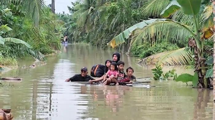 BANJIR LANGKAT - Suasana masyarakat Desa Batu Melenggang, Kecamatan Hinai, Kabupaten Langkat, Sumatera Utara, saat mengungsi ke tempat yang lebih aman akibat rumah mereka terendam banjir, Jumat (28/11/2025).