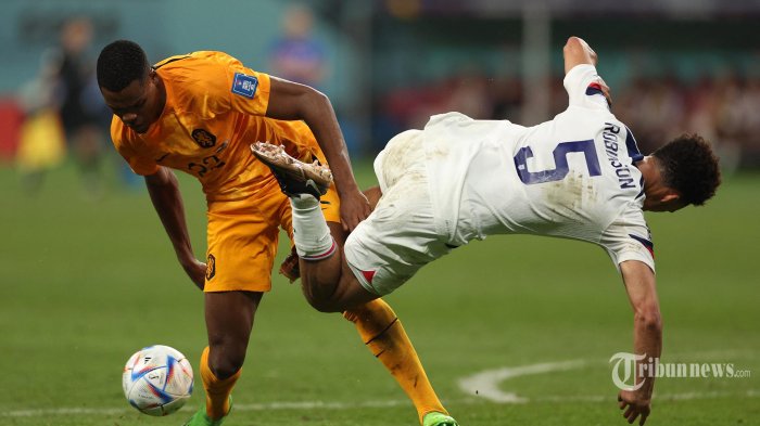 Bek Belanda Denzel Dumfries (kiri) bertarung memperebutkan bola dengan bek AS Antonee Robinson selama pertandingan sepak bola babak 16 besar Piala Dunia Qatar 2022 antara Belanda dan AS di Stadion Internasional Khalifa di Doha pada 3 Desember 2022. (Adrian DENNIS/AFP)
