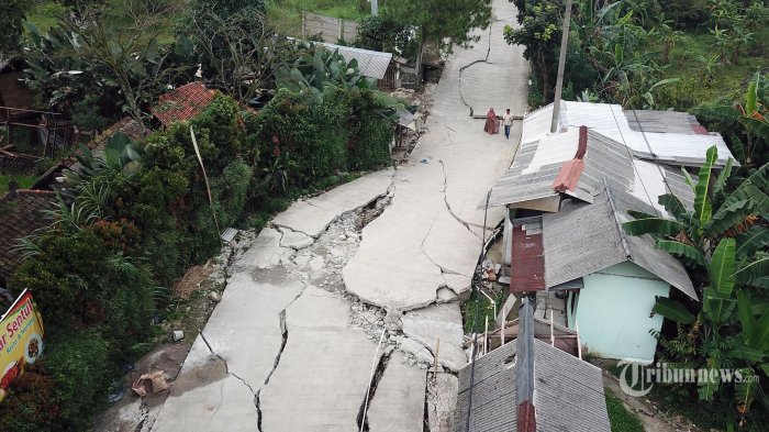 Warga melintas di jalan yang terbelah akibat pergerakan tanah di Kampung Curug, Desa Bojongkoneng, Kecamatan Babakanmadang, Kabupaten Bogor, Jawa Barat, Jumat (16/9/2022). Badan Penanggulangan Bencana Daerah (BPBD) Kabupaten Bogor mencatat akibat pergeseran tanah, 18 unit rumah mengalami kerusakan serta menyebabkan retakan-retakan di tanah, dinding, plafon dan lantai rumah warga serta akses jalan sudah tidak bisa dilewati oleh kendaraan roda empat.Wartakotalive.com/Alex Suban