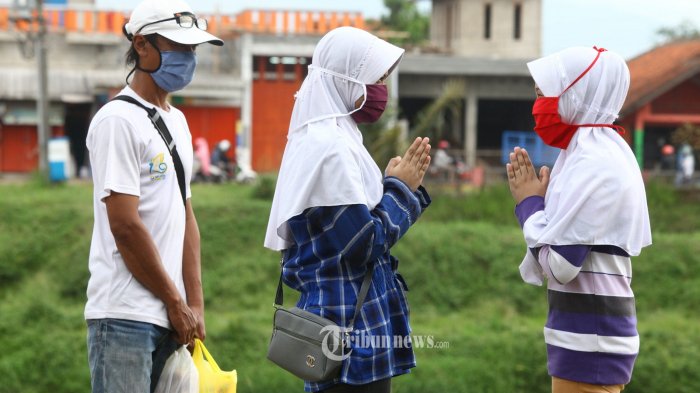 Umat muslim bersalaman tanpa bersentuhan di saat pandemi Covid-19 pada H+1 Lebaran di kawasan Kabupaten Bandung, Senin (25/5/2020). Langkah yang dilakukan tersebut guna mencegah penyebaran Covid-19 agar tidak semakin meluas. (TRIBUN JABAR/GANI KURNIAWAN)