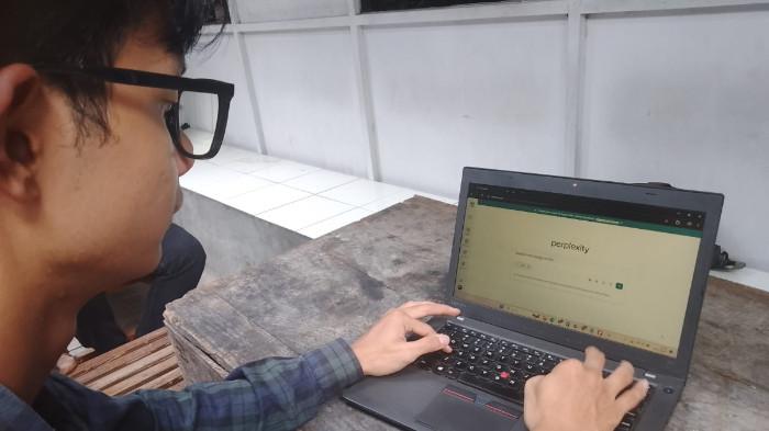 GUNAKAN AI - Mahasiswa Universitas Muhammadiyah Surakarta (UMS), Zaky Mohammad Rizwar (19) menatap layar laptopnya yang sedang membuka sebuah platform AI.