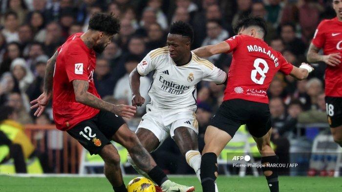 Penyerang Real Madrid Brasil Vinicius Junior bersaing dengan gelandang Portugal Real Mallorca Samu Costa dan gelandang Spanyol Real Mallorca Manuel Morlanes selama pertandingan sepak bola liga Spanyol antara Real Madrid CF dan RCD Mallorca di stadion Santiago Bernabeu di Madrid pada 3 Januari , 2024.