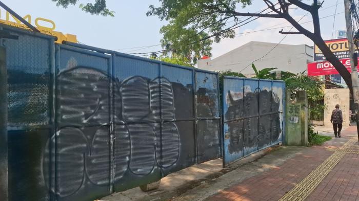 MOTOR EMMO - Kondisi gerbang utama showroom Emmo Electric Mobility di Jalan Daan Mogot, Grogol Petamburan, Jakarta Barat, Senin (13/4/2026). Meski tercantum sebagai showroom pertama di laman resmi perusahaan, bangunan yang berdiri di atas lahan bekas gudang ini tampak masih dalam tahap renovasi dan belum melayani transaksi kendaraan untuk program Makan Bergizi Gratis (MBG).