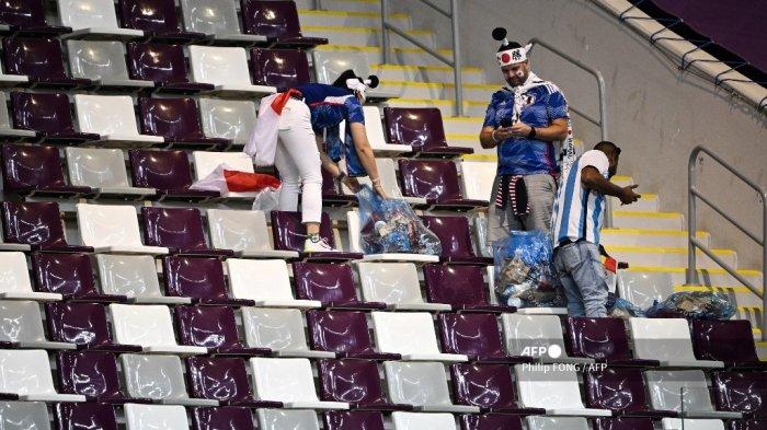 Pendukung Jepang memungut sampah di tribun penonton pada akhir pertandingan sepak bola Grup E Piala Dunia 2022 Qatar antara Jepang dan Spanyol di Stadion Internasional Khalifa di Doha pada 1 Desember 2022.