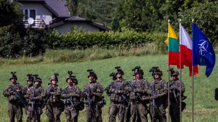 Tentara Polandia bersenjata berdiri selama konferensi pers presiden Polandia dan Lituania setelah kunjungan bersama pusat komando seluler Divisi Multinasional NATO Timur Laut dekat desa Szypliszki, yang terletak di Celah Suwalki - bentangan Polandia sepanjang 80 kilometer -Perbatasan Lituania diapit antara Kaliningrad dan Belarusia, di timur laut Polandia, pada 7 Juli 2022. Wojtek RADWANSKI / AFP