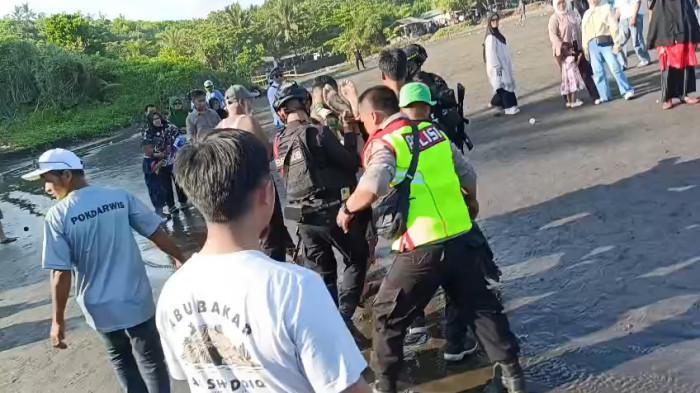 TEWAS TOLONG BOCAH - Tangkapan layar video Petugas gabungan tengah mengevakuasi seorang wisatawan yang meninggal usai menolong bocah yang terseret ombak pantai Karang Tawulan, Cikalong, Kabupaten Tasikmalaya, Jawa Barat, Senin (23/3/2026) sore