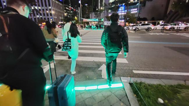 Lampu Lalu Lintas di Trotoar Seoul Memandu Pejalan Kaki yang Sibuk Berponsel