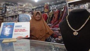 Sri-Maryati-menunjukkan-papan-penghargaan-dari-BRI-atas-prestasinya-dalam-transaksi-QRIS.jpg