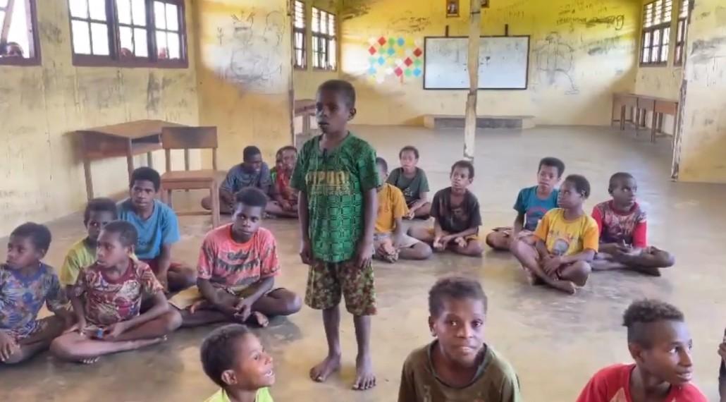 MEMBACA LIRIK LAGU - Tangkap layar momen Rino Pasim, siswa SDN Atti, Distrik Minyamur, Kabupaten Mappi, Papua Selatan saat membaca lirik lagu Tanah Airku di kelasnya.